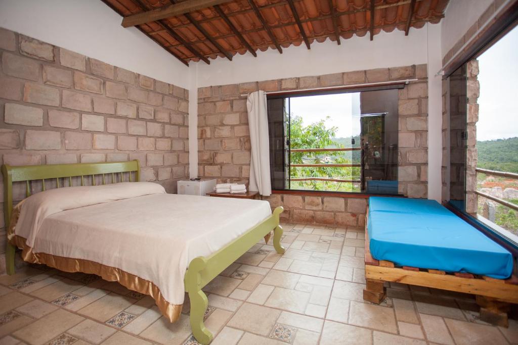 a bedroom with a bed and a large window at Beija- flor de Lençóis in Lençóis