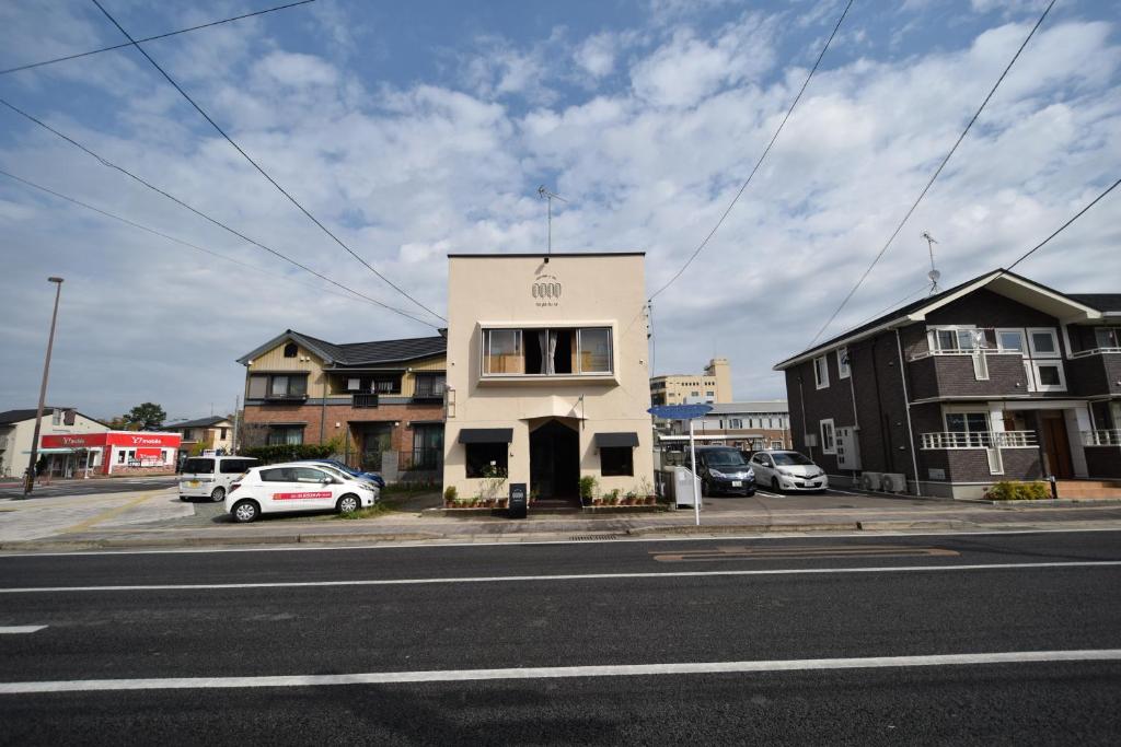 a white building on the side of a street at Saga International Guesthouse Hagakure in Saga