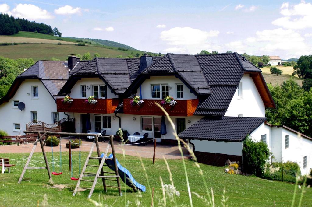 une maison avec une aire de jeux en face dans l'établissement Schweizes Ferienhof, à Medebach