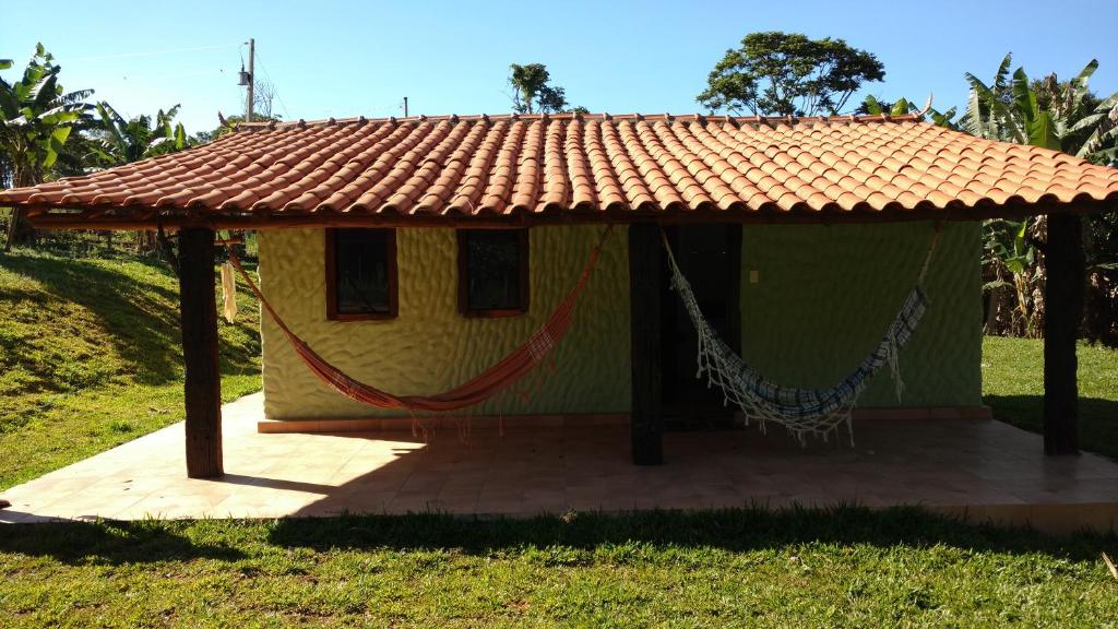 a small house with a hammock in a field at Sossego Da Mata in Santo Antônio do Leite