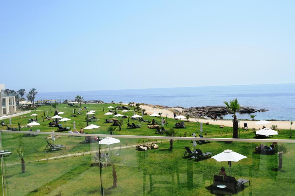 un parco con ombrelloni bianchi e l'oceano di Amphora Hotel & Suites a Paphos