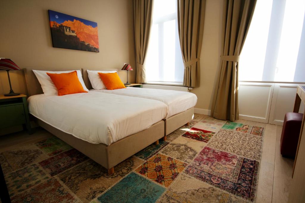 a bedroom with a large bed with orange pillows at Hooome in Brussels