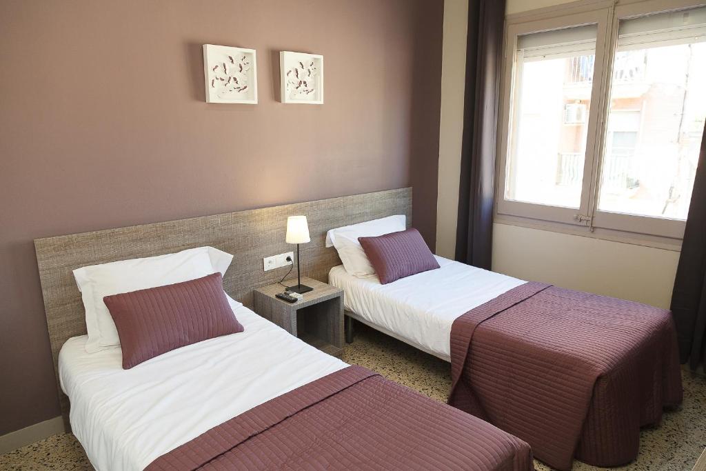 坎布里爾斯的住宿－Hostal Fonda Montserrat，酒店客房设有两张床和窗户。