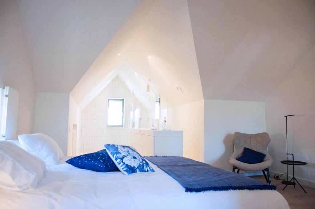 een slaapkamer met een groot wit bed en een stoel bij Maison Village in Noorbeek