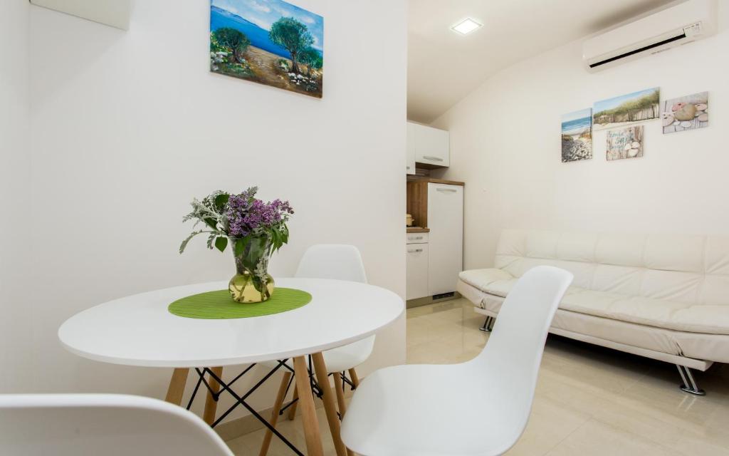 a white dining room with a white table and white chairs at Apartments Mira in Baška