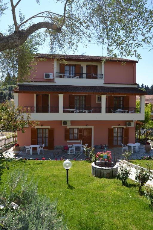 un gran edificio rosa con un jardín delante de él en Anna Apartments en Kontokali