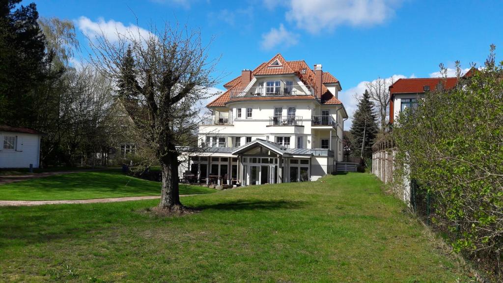 a large white house with a tree in the yard at Hotel Villa Passion in Malchow