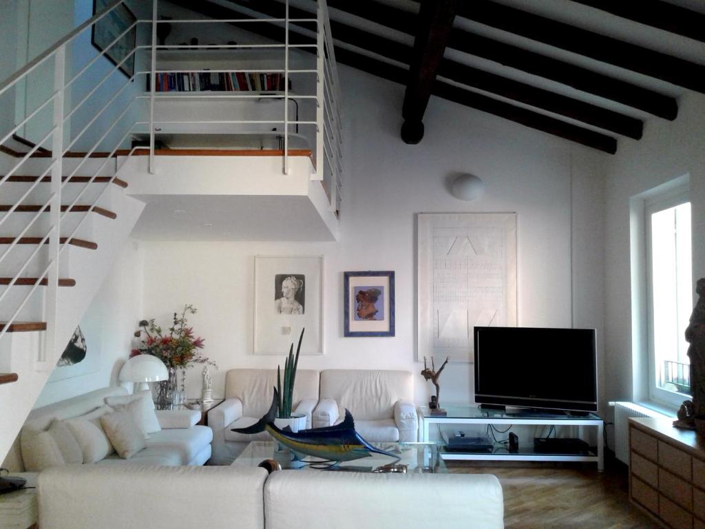 a living room with white furniture and a staircase at B&B Griffoni 7 in Bologna