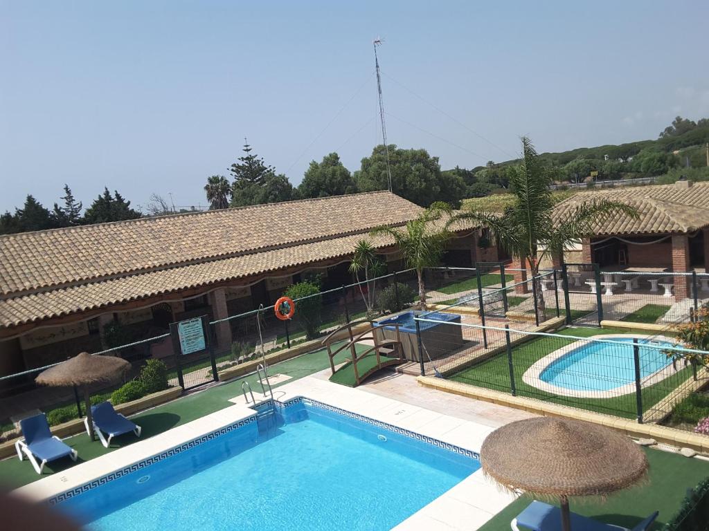 a pool with chairs and umbrellas next to a building at Residencial La Teja in Zahora