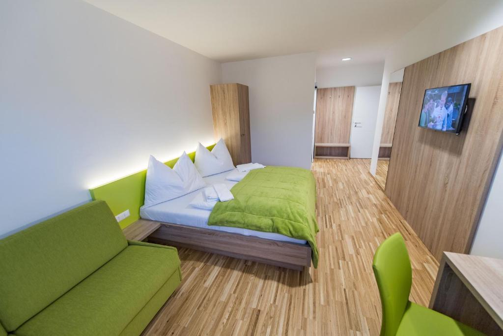 - une chambre avec un lit vert et un canapé dans l'établissement Hotel Restaurant Meyer, à Kalsdorf bei Graz