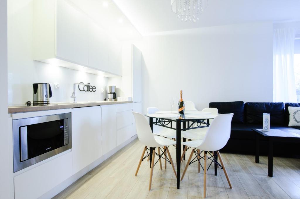 a kitchen and living room with a table and chairs at Apartament z basenem Polanki in Kołobrzeg