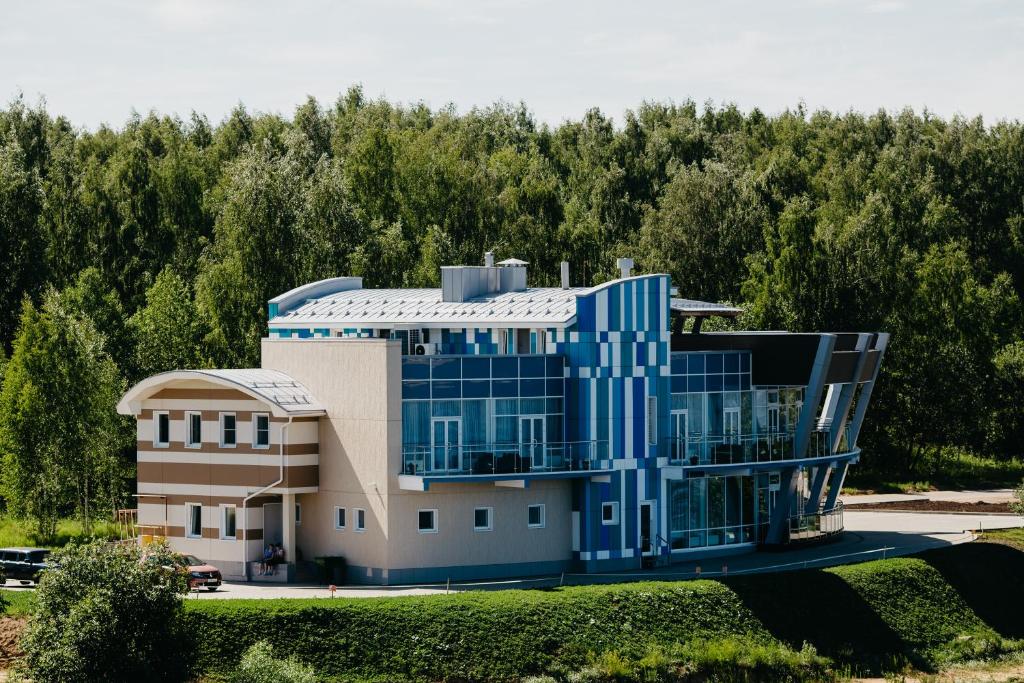a large blue building with trees in the background at Cruise Hotel in Kostroma