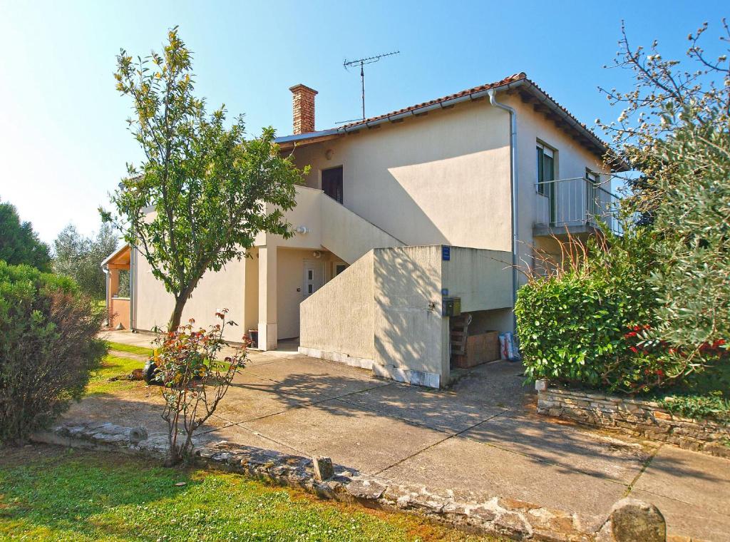 ein weißes Haus mit einem Baum davor in der Unterkunft Apartments Duilija 1301 in Barbariga