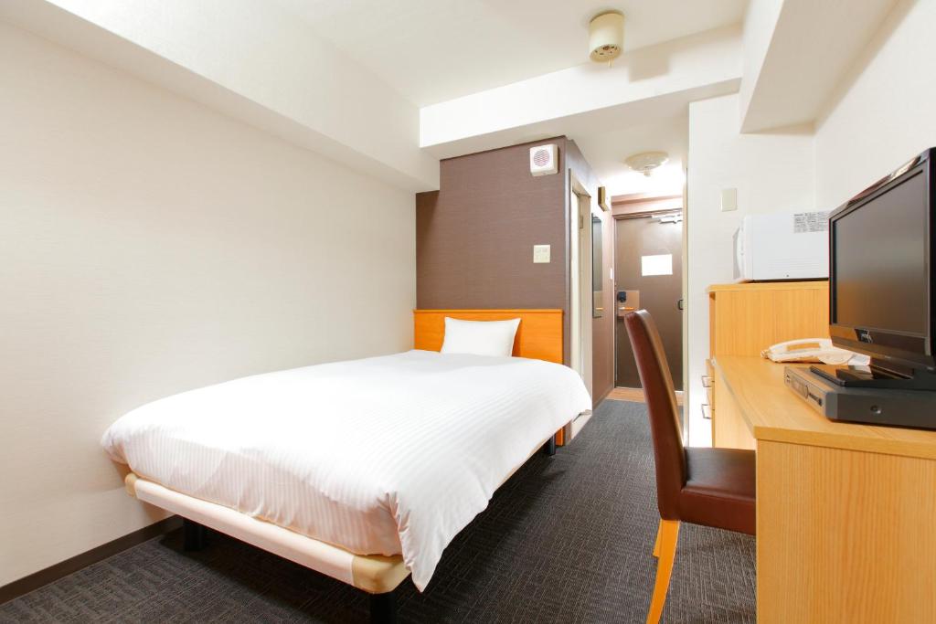 FLEXSTAY INN Shirogane في طوكيو: غرفة نوم مع سرير ومكتب مع تلفزيون