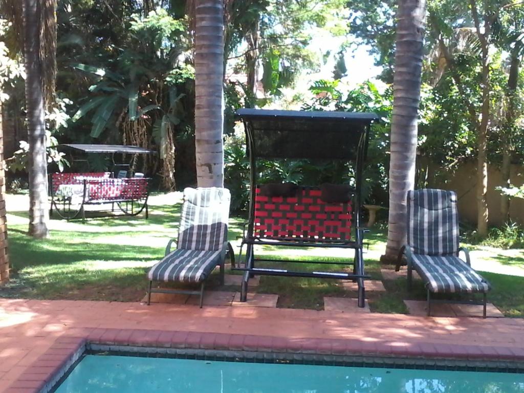 a group of three chairs sitting next to a pool at Montana Boutique Guesthouse in Pretoria