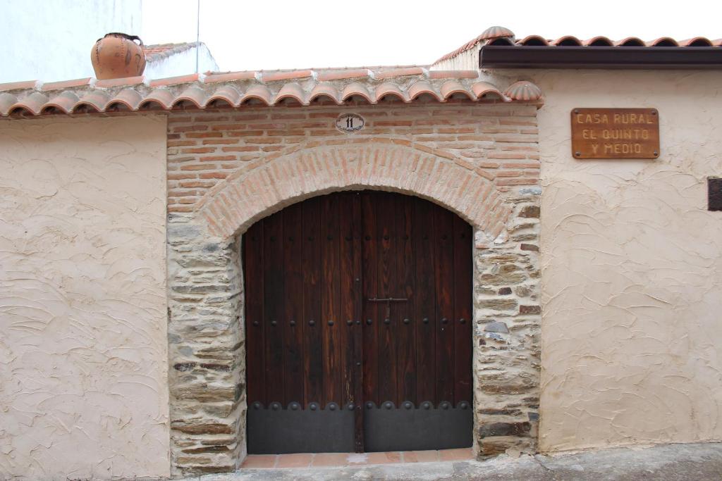 a brick building with a large wooden door at Casa Rural El Quinto y Medio in Valdelacasa de Tajo