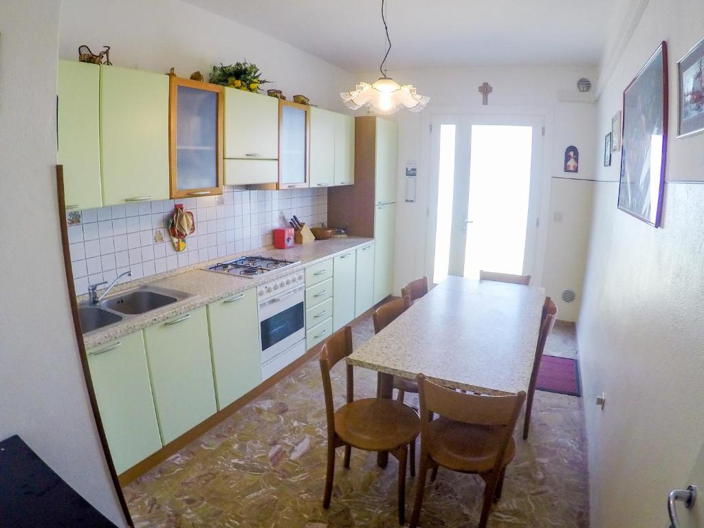 a kitchen with green cabinets and a table and chairs at Condominio Sole - Agenzia Cocal in Caorle
