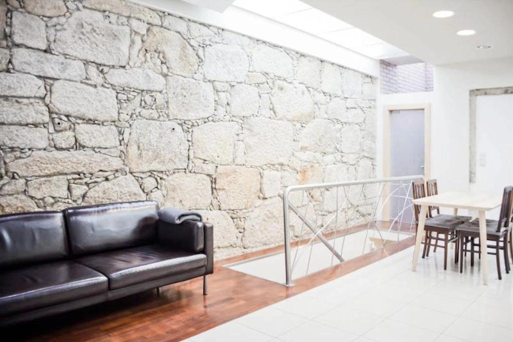 a black leather couch in a room with a stone wall at House Cedofeita in Porto