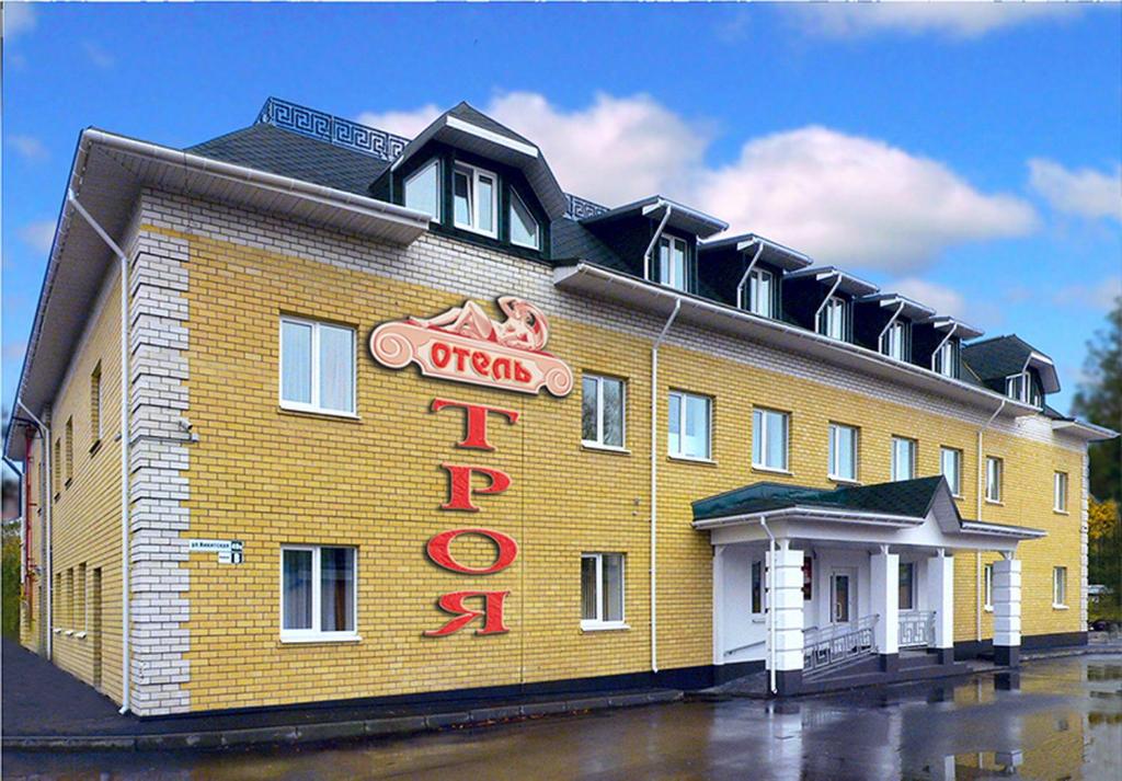 a yellow building with a red neon sign on it at Hotel Troya in Kostroma