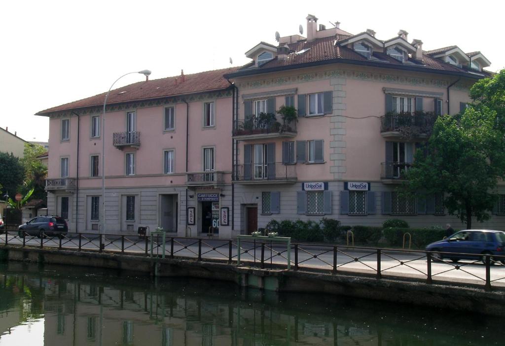 a building next to a river with cars parked in front at Le Residenze Della Poetessa in Corsico