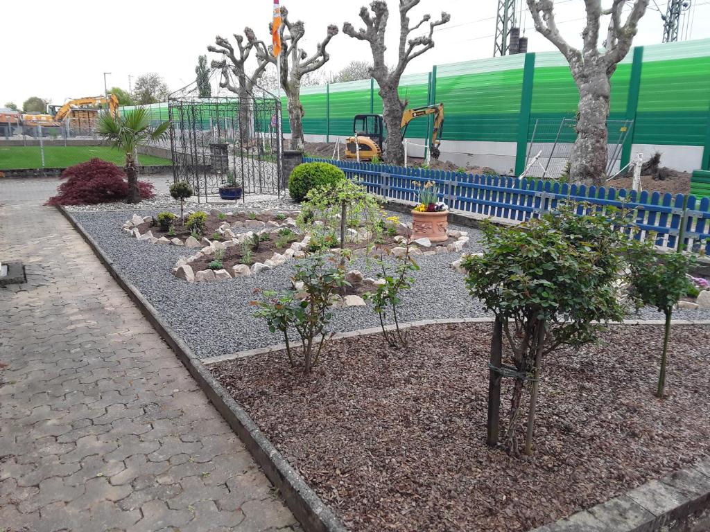 a garden with trees and rocks in front of a train at Ferienwohnung Müller in Kenzingen