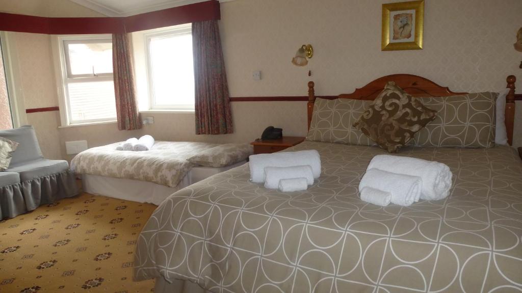 een hotelkamer met een bed en een stoel bij Whitehall Guest House in Colwyn Bay