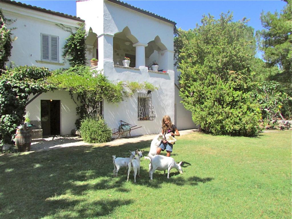 Una ragazza con un bambino e una pecora davanti a una casa di Agriturismo "Borgo Madonna degli Angeli" - charming cottages in the gardens ! a Tocco da Casauria