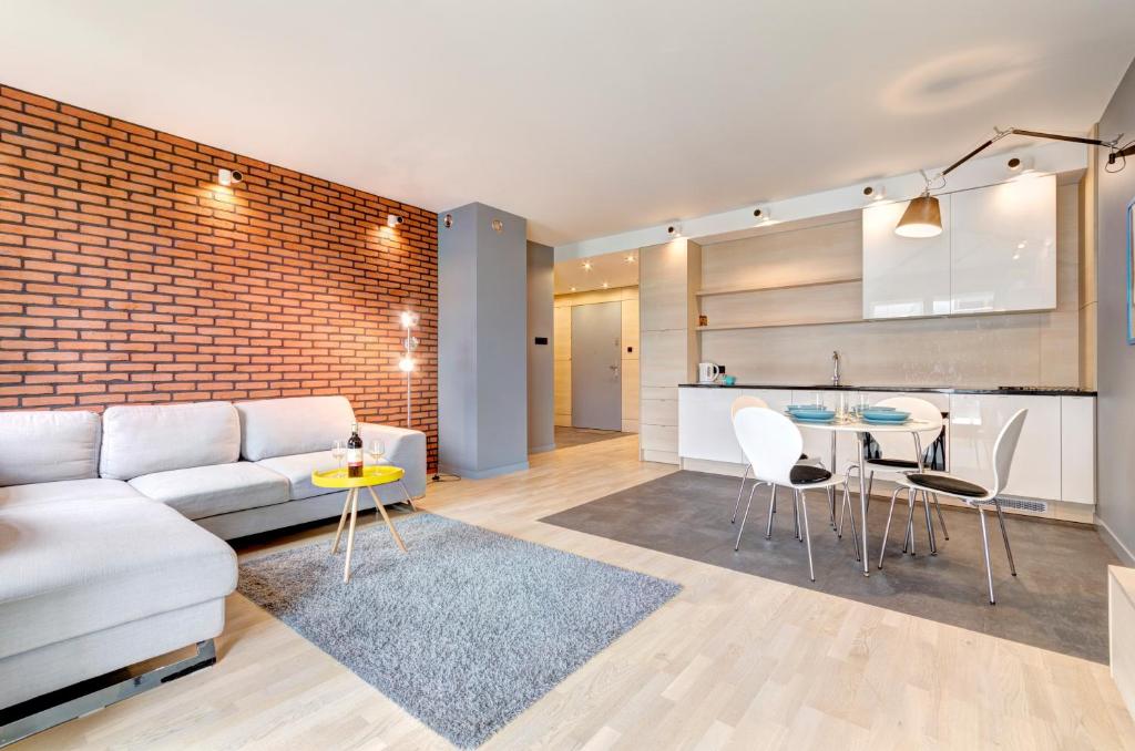 Dom & House - Apartamenty Sopocka Przystań في سوبوت: غرفة معيشة مع أريكة بيضاء ومطبخ