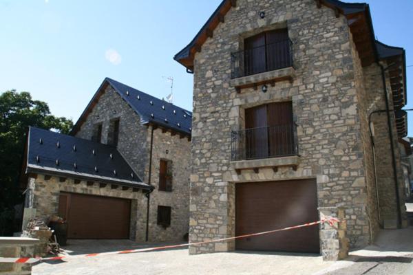 a large brick building with two garage doors at Hostal Rural Casa Parda in Tramacastilla de Tena
