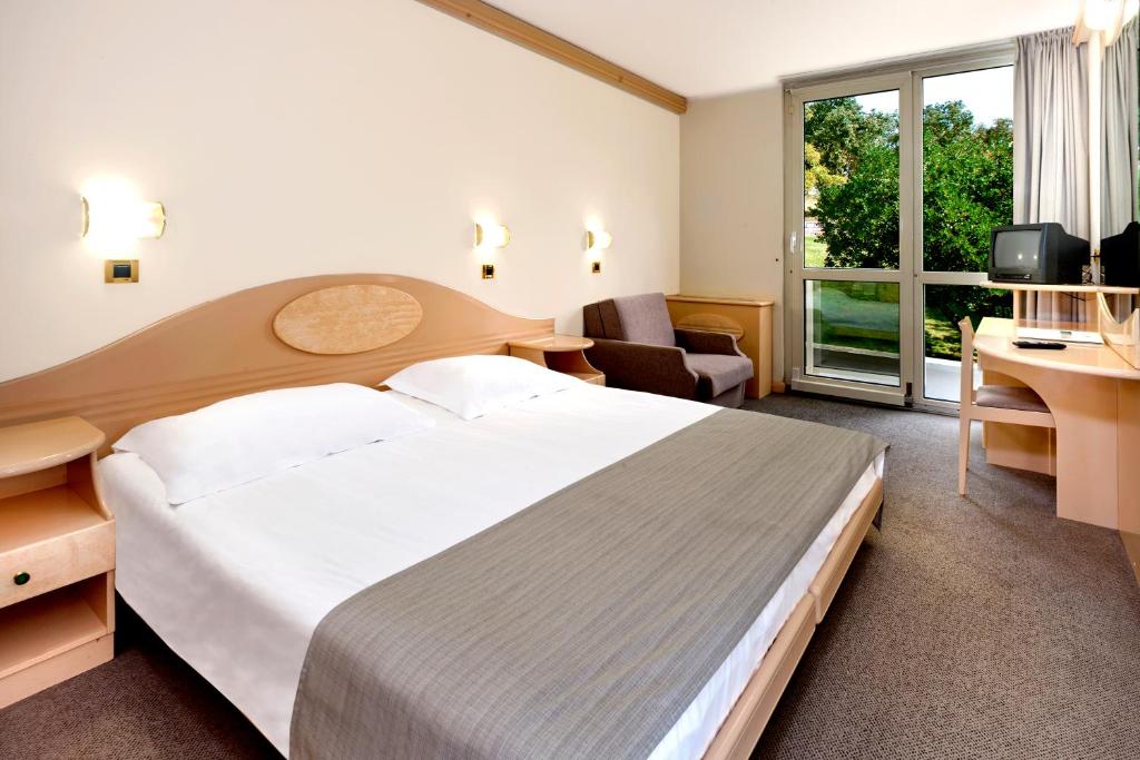 a hotel room with a large bed and a desk at Hotel Istra Plava Laguna in Poreč