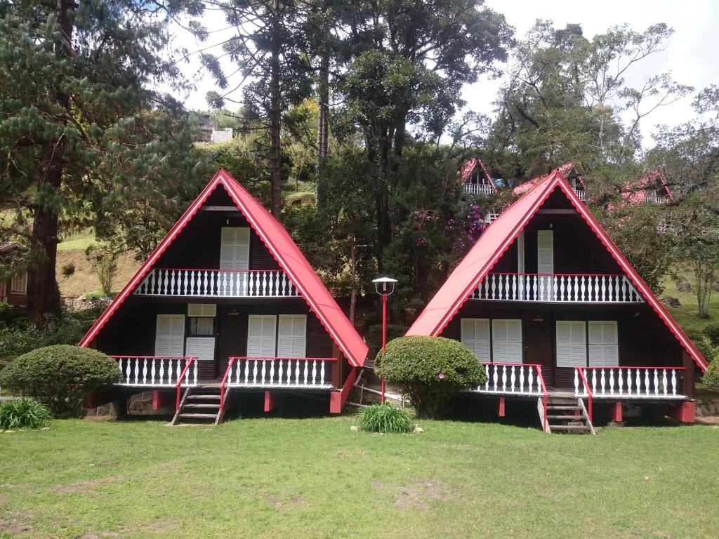 a home with two red roofs on the grass at Pousada Duas Quedas in Campos do Jordão