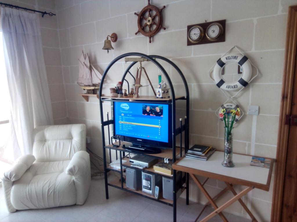 a living room with a tv and a chair at Coral Reef Flat 7 in Marsalforn