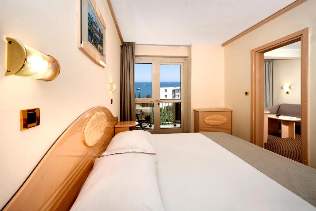 a hotel room with a bed and a window with a view at Hotel Istra Plava Laguna in Poreč