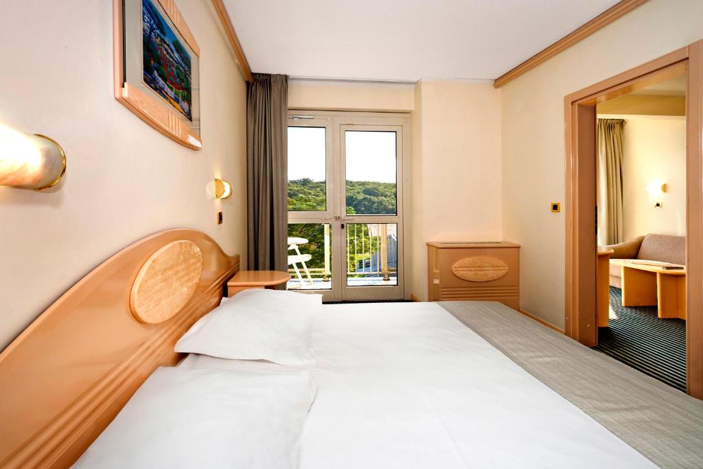 a hotel room with a bed and a window at Hotel Istra Plava Laguna in Poreč