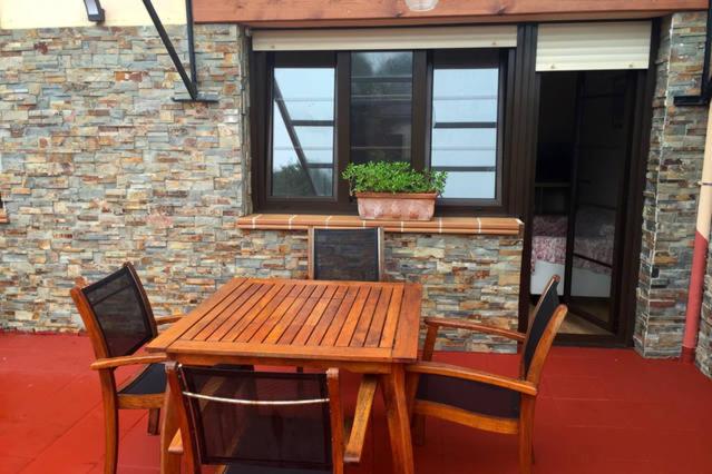 una mesa de madera y sillas con una maceta en el patio en Pensión Las Barqueras, en Llanes