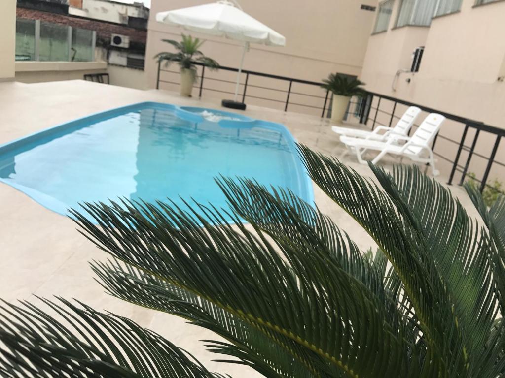 a blue swimming pool on a balcony with a palm tree at Resende Inn in Resende