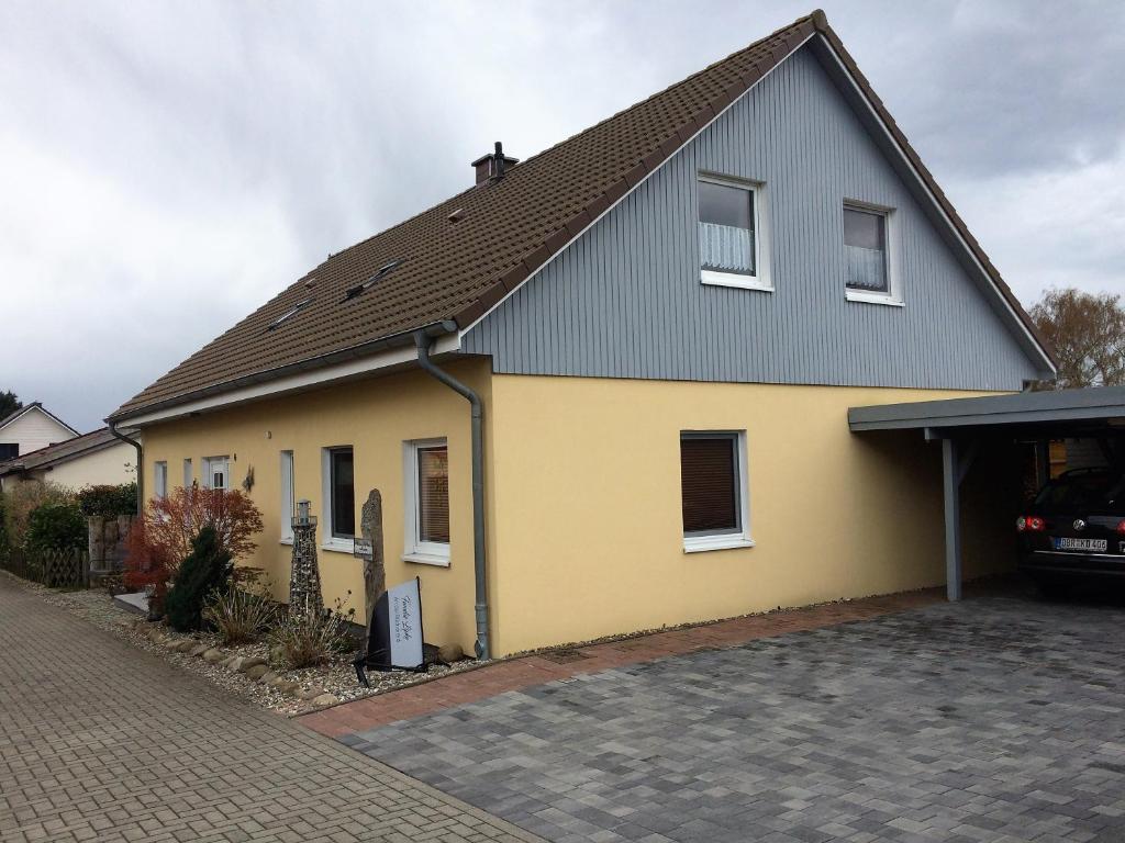 ein gelbes und graues Haus mit Auffahrt in der Unterkunft Apartment An der Büdnerei in Graal-Müritz