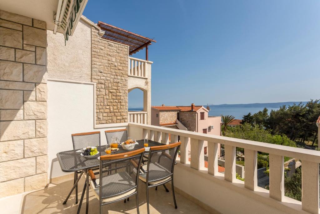 a balcony with a table and chairs and a view of the ocean at Apartments Biserka in Bol