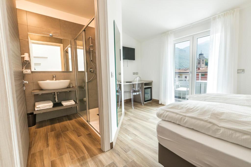 a bedroom with a bathroom with a sink and a tub at Albergo Garni Francesco in Nago-Torbole