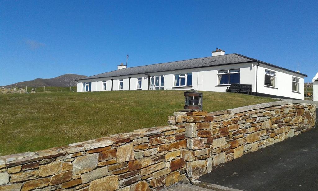 a white house with a stone wall in front of it at Achill West Coast House in Dooagh