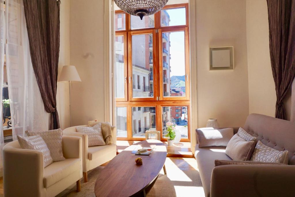 a living room with couches and a table and a large window at Monappart Cristo Historic Apartment with Parking in Bilbao