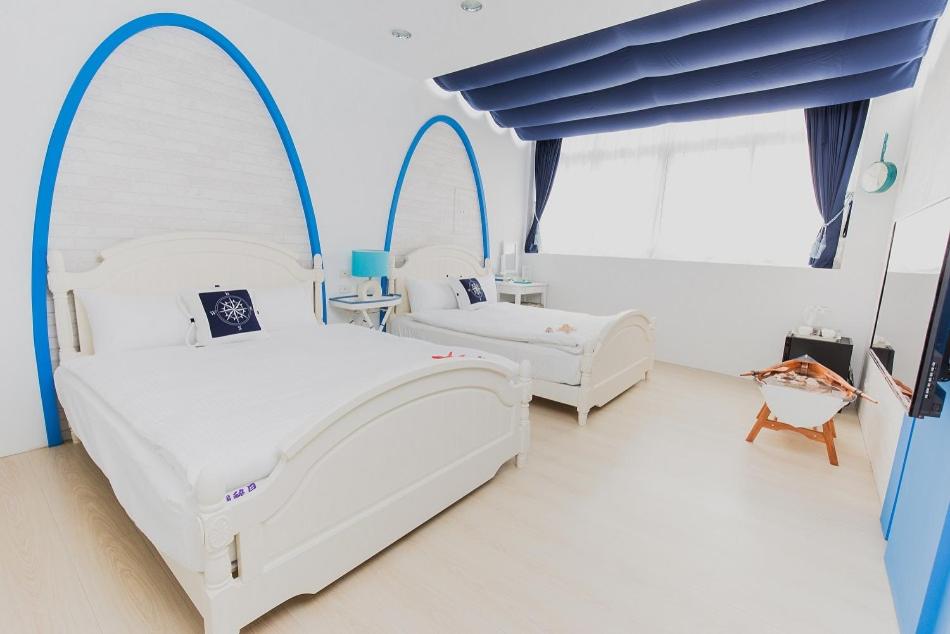 2 camas blancas en una habitación con ventanas arqueadas en Welcome The Sun Enjoy The Moon, en Kaohsiung