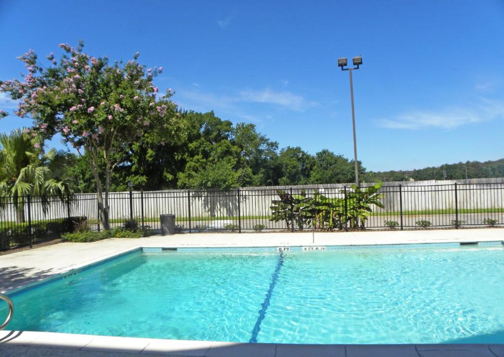 a swimming pool with blue water in front of a fence at Suburban Studios Houston North I-45 in Houston