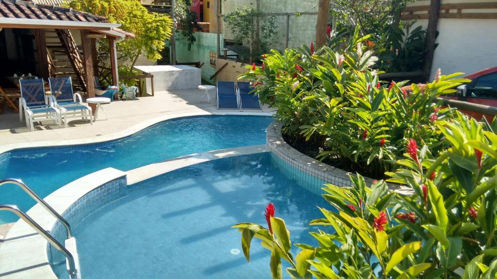 a swimming pool with plants and chairs in a yard at Pousada Mareilha in Ilhabela