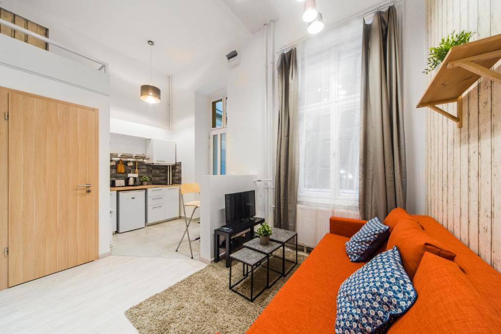 ブダペストにあるAstoria Airconed 1 Bedroom Apartmentのリビングルーム(オレンジ色のソファ付)、キッチンが備わります。