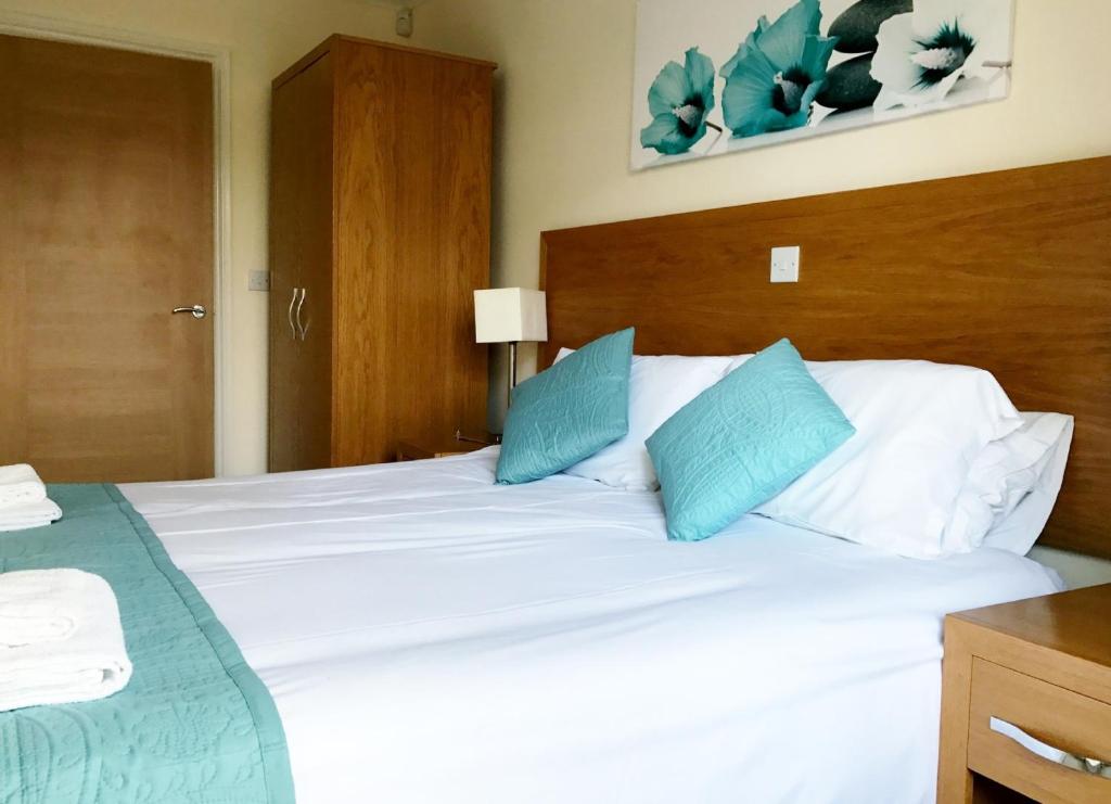 - une chambre avec un grand lit blanc et des oreillers bleus dans l'établissement Hartford Court, à Bournemouth