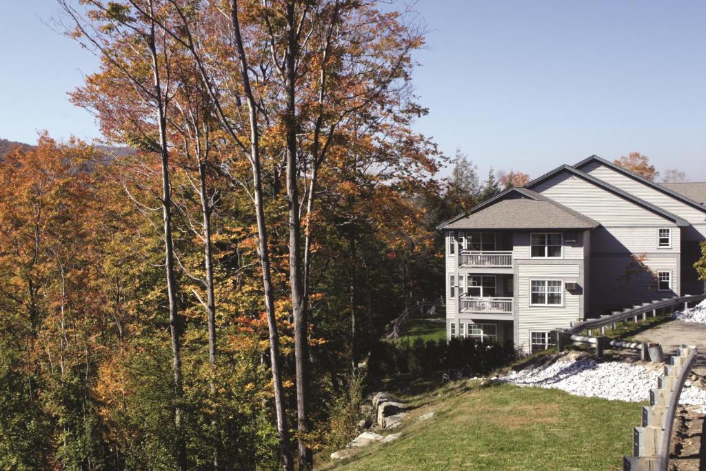 a white house with trees in front of it at Club Wyndham Smugglers' Notch Vermont in Jeffersonville