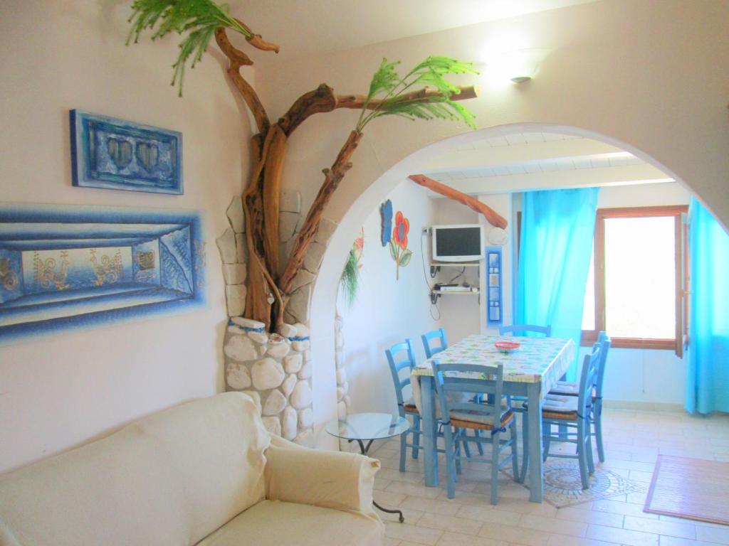 a living room with a table and a tree at Sardinia Yellow House in Solanas