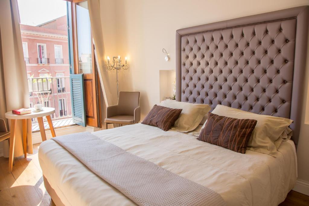 a bedroom with a large bed and a large window at Antico Corso Charme in Cagliari