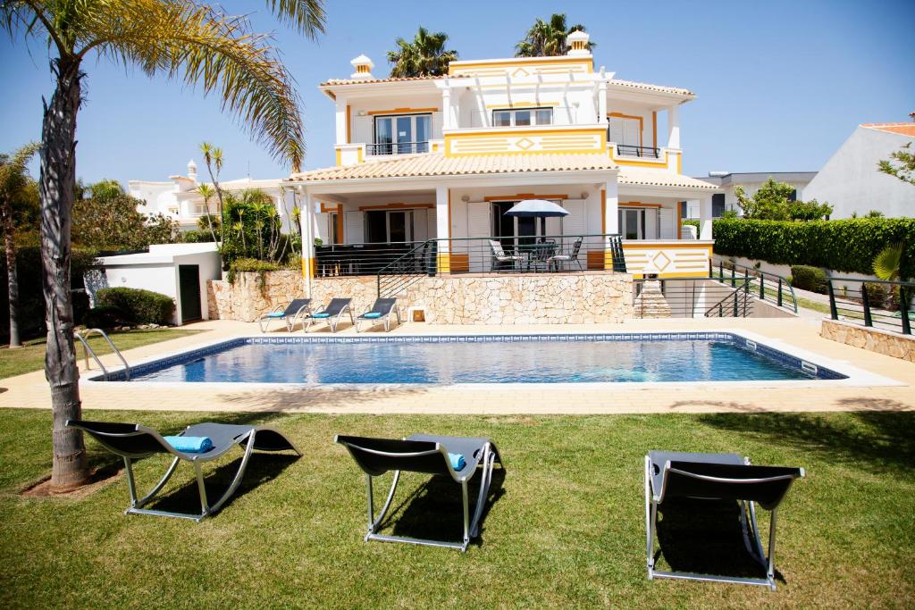 uma casa com piscina e duas espreguiçadeiras em Villa Clara Premium by Sunny Deluxe em Albufeira